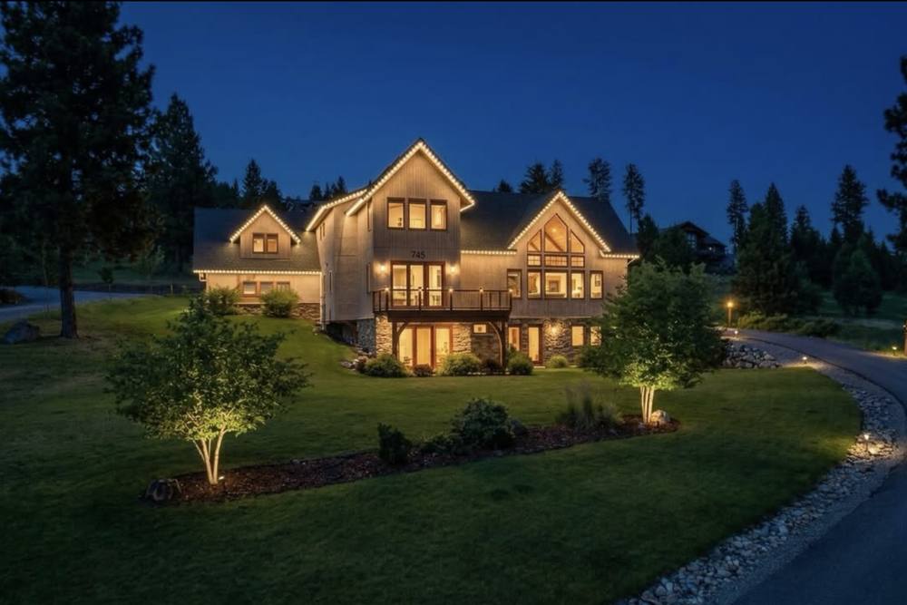 Mountain craftsman home at night with warm lights following each gable